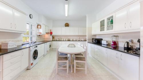 una cucina con armadi bianchi e tavolo bianco di Sunny & Calm 4 BDR House W/ Pool by Lovelystay a Santo Estêvão