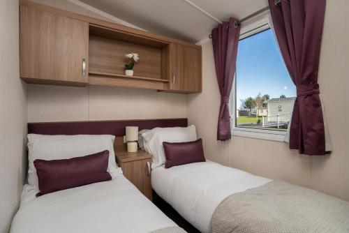 two beds in a small room with a window at CALI - 3Bed - Static Caravan in Port Seton