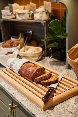 a cutting board with a loaf of bread and a knife at Home Hotel Smedjan in Sandviken