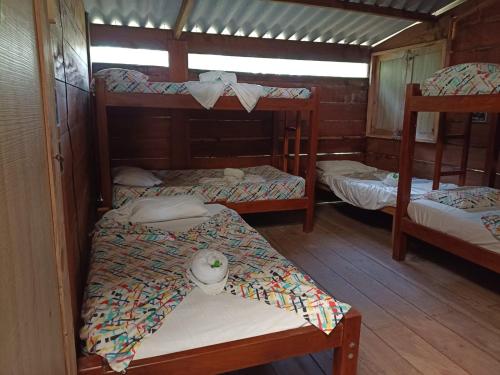 a room with three bunk beds in a cabin at Casa hostal playa coral in Capurganá