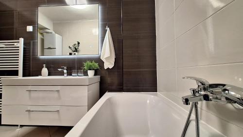 a bathroom with a tub and a sink and a mirror at Apartman Lucille in Osijek