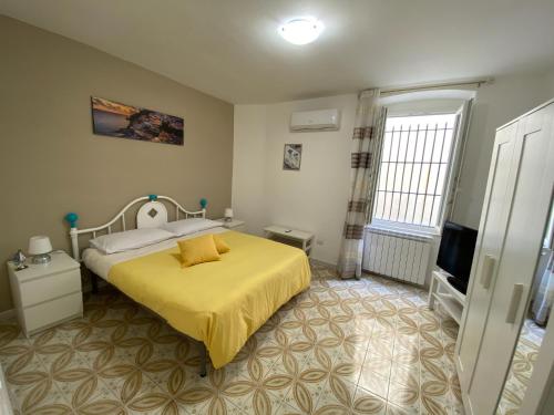 1 dormitorio con cama amarilla y TV en Casa vacanza: The Wind Rose, en Vietri