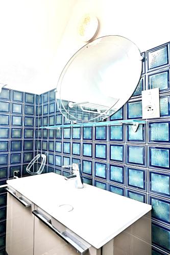 La salle de bains est pourvue de murs carrelés bleus et d'un miroir. dans l'établissement Appartement familial à Juncalas, 70 m² avec jardin privé !, à Juncalas