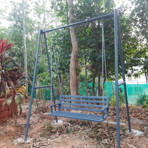a blue swing in a park with a tree at White Rose in Chekadi