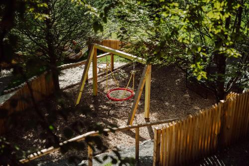 a swing set in a yard next to a fence at Familien- & Gartenhotel Theresia 4-Sterne Superior in Saalbach Hinterglemm