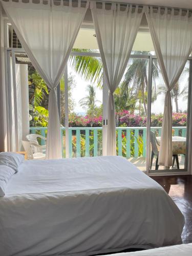 ein Schlafzimmer mit einem weißen Bett und einem Balkon in der Unterkunft Siete Mares in Brisas de Zicatela