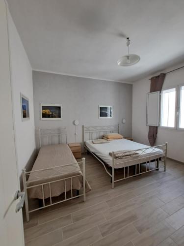 トッレ・オヴォにあるVilla Lory Torre Ovoの白い壁とウッドフロアの客室で、ベッド2台が備わります。