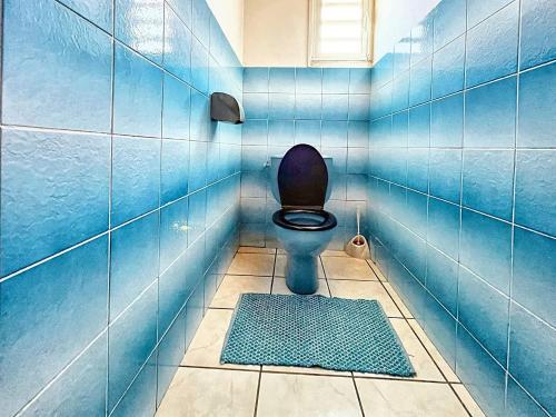 a blue tiled bathroom with a toilet and a rug at Maison idyllique à Saint-Leu avec vue sur la mer. in Saint-Leu