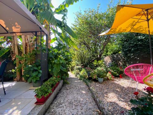 Maison Belmont Eymet في إيميت: حديقة فيها مظلة صفراء وبعض النباتات