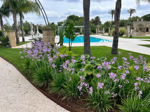 a garden with purple flowers next to a swimming pool at Villa Anna - Suites & Events in Specchia