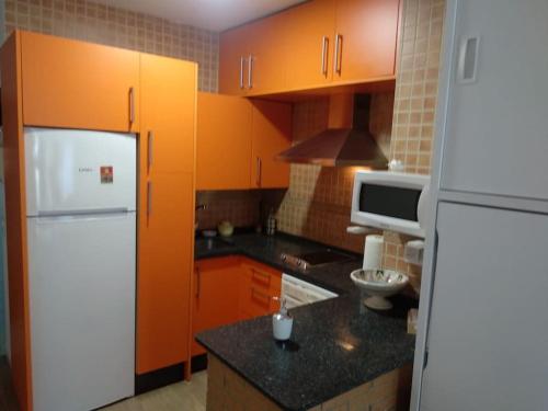 - une cuisine avec des armoires orange et un réfrigérateur blanc dans l'établissement Estudio con acceso privado y directo a la Playa, à Isla Cristina