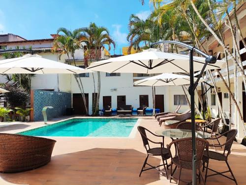 - une piscine avec des tables et des parasols à côté de la piscine dans l'établissement Pousada Estalagem dos Corais da Prainha, à Arraial do Cabo