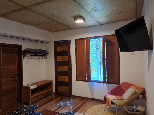 ein Wohnzimmer mit einem Sofa und einem TV an der Wand in der Unterkunft Chalé Antúrios - Lavras Novas in Lavras Novas