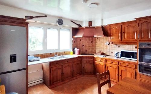 une cuisine avec des placards en bois et une grande fenêtre dans l'établissement Majestueuse maison à Bondy - 200 m² - 10 pers. & parking, à Bondy