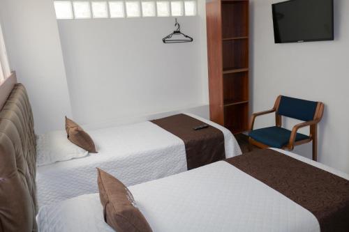 Pokój hotelowy z 2 łóżkami i krzesłem w obiekcie Hotel Casa Botero 101 w mieście Bogota