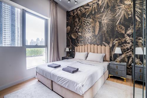 a bedroom with a large bed with a tropical wallpaper at Seaside, renewed poshy apartment on JBR in Dubai
