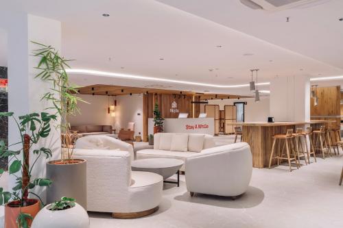 a lobby with white chairs and tables and a bar at SKYLA Studios & Suites - Kondapur in Hyderabad