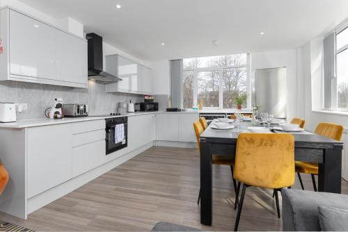 Flatzy - 16 Guests 4 En-suite Central Apartment B في ليفربول: مطبخ مع طاولة سوداء وكراسي صفراء