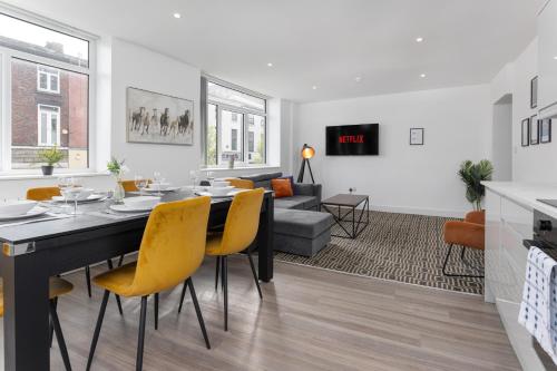 Flatzy - 16 Guests 4 En-suite Central Apartment B في ليفربول: غرفة طعام وغرفة معيشة مع طاولة وكراسي صفراء