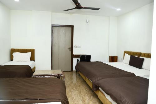 a room with two beds and a ceiling fan at Hotel Kiwi Inn in Indore