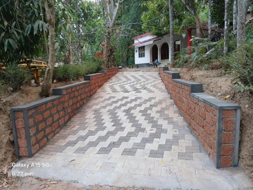 a brick wall and a walkway in front of a house at White Rose in Chekadi