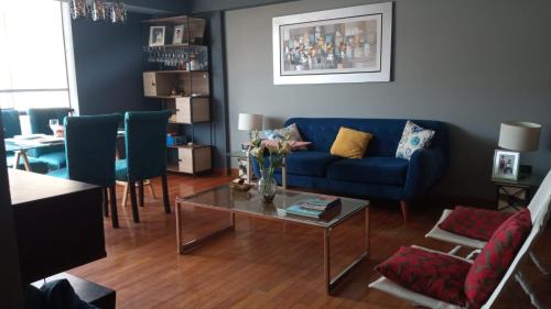 リマにあるApartamento amplio, tranquilo y centricoのリビングルーム(青いソファ、テーブル付)