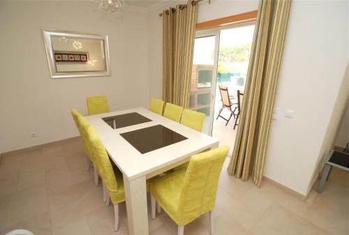 a dining room with a white table and yellow chairs at Vila Pluma Rosa in Amoreira