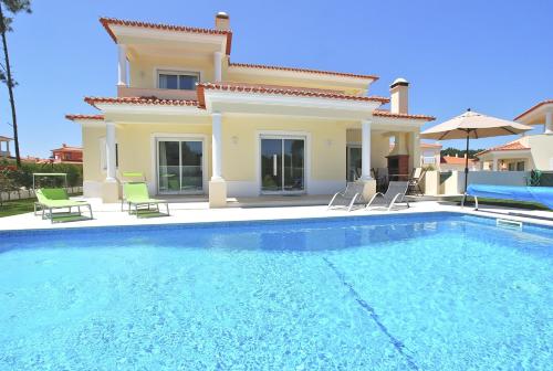 a villa with a swimming pool in front of a house at Vila Pluma Rosa in Amoreira