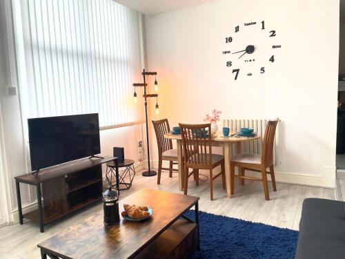 a living room with a table and a clock on the wall at Cosy Prenton home near Tranmere Club and Liverpool in Birkenhead