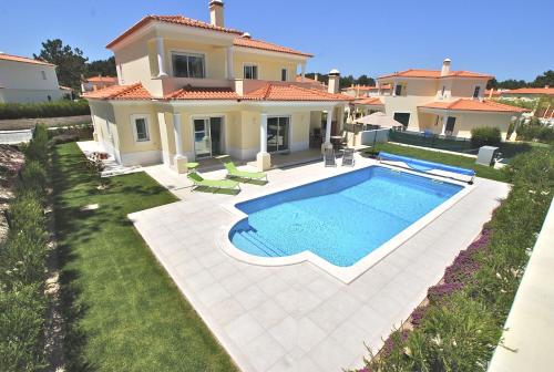 a villa with a swimming pool in front of a house at Vila Pluma Rosa in Amoreira