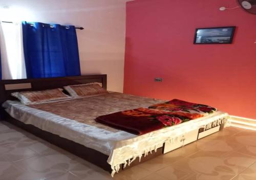 a bed in a room with a red wall at White Rose in Chekadi