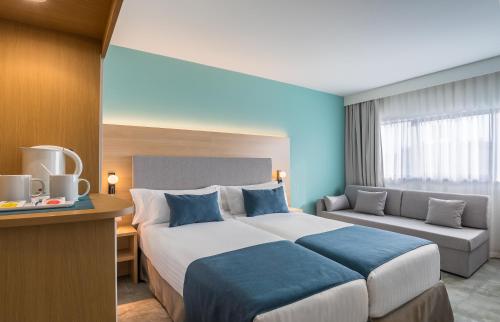 a hotel room with a large bed and a couch at Occidental Murcia Agalia in Murcia