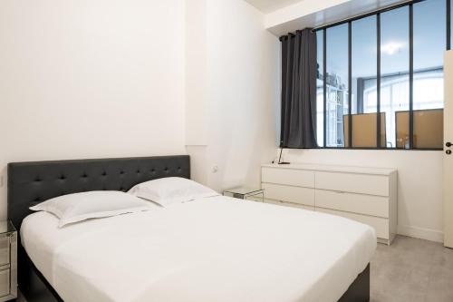 une chambre blanche avec un grand lit et une fenêtre dans l'établissement Veeve - Halles Heaven, à Paris