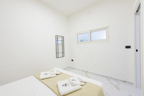 ein weißes Zimmer mit zwei Betten und einem Fenster in der Unterkunft Salentin Home - WindRelax in San Pietro in Bevagna