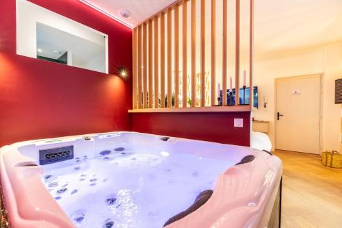 - un bain à remous dans une chambre dotée d'un mur rouge dans l'établissement Loveroom en centre ville avec jacuzzi - Notre dame, à Clermont-Ferrand