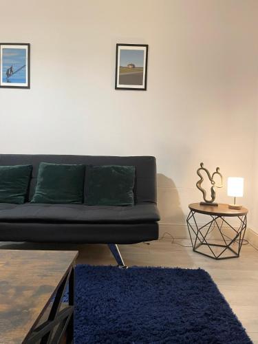 a living room with a black couch and a table at Cosy Prenton home near Tranmere Club and Liverpool in Birkenhead