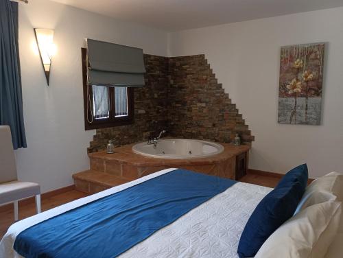 a bedroom with a bed and a tub and a sink at Hotel Rural los Tadeos in Zahara de la Sierra