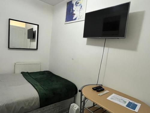 a room with a bed and a television on the wall at Home Away in London