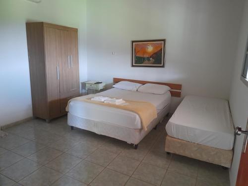 a bedroom with two beds and a cabinet at Hotel Fazenda Recanto do Monte Alegre in Piraju