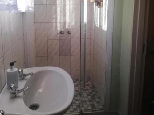 a bathroom with a white sink and a shower at the FARMHOUSE BOUTIQUE GUESTHOUSE AND BEERGARDEN CC in Outjo