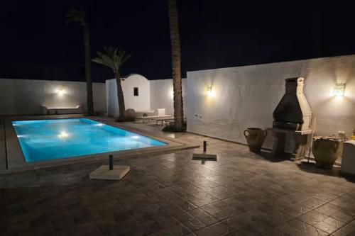 a swimming pool in a courtyard at night at villa izabelles in Djerba