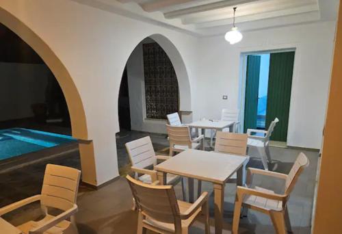 a dining room with tables and chairs and a pool at villa izabelles in Djerba