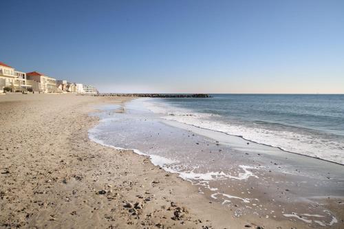 une plage de sable avec des maisons et l'océan dans l'établissement T2 Le Plénitude Vue Mer Palavas, à Palavas-les-Flots