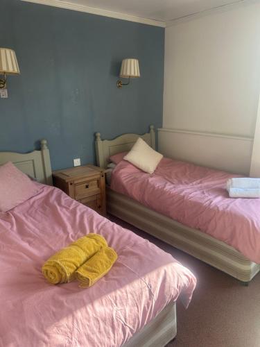 a room with two beds with yellow towels on them at Tayleur arms in Crudgington