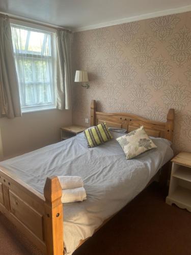 1 dormitorio con cama de madera con 2 almohadas y ventana en Tayleur arms, en Crudgington