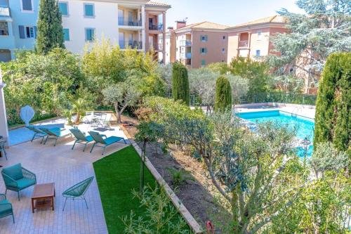 un jardin avec une piscine et des chaises ainsi qu'un bâtiment dans l'établissement Anaïs de Saint-Tropez, Bel appartement, avec piscine et jardin, au cœur de Saint Tropez, à Saint-Tropez