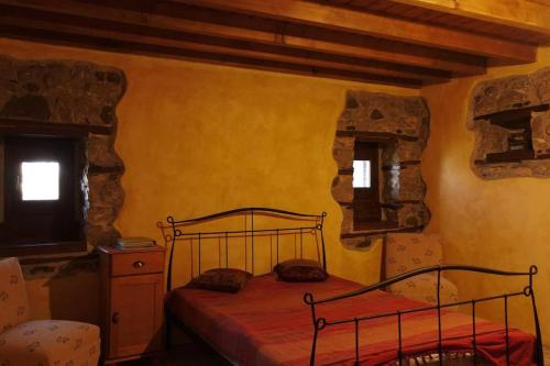 een slaapkamer met een metalen bed in een kamer met 2 ramen bij Picturesque double flat country house in Thrapsímion