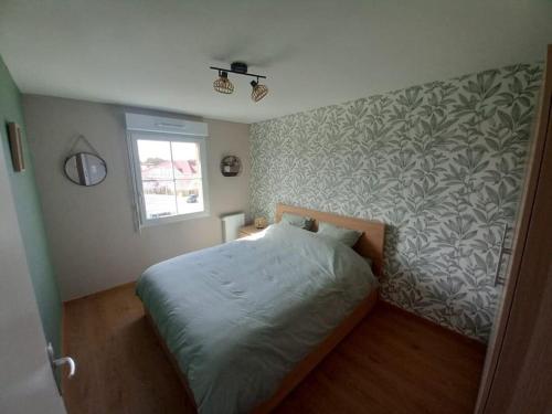 Ce lit se trouve dans une chambre dotée d'un mur. dans l'établissement Appartement neuf bien situé à Sainte Cécile Plage, à Camiers