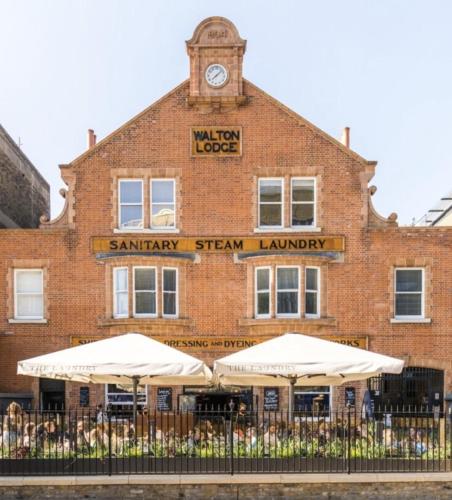 a brick building with a clock tower on top of it at Artistic Pied-à-Terre, Steps from the Tube, Moments from London's Heart in London