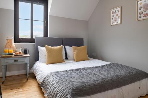 a bedroom with a bed with white sheets and yellow pillows at The Lookout, Burry Port in Burry Port